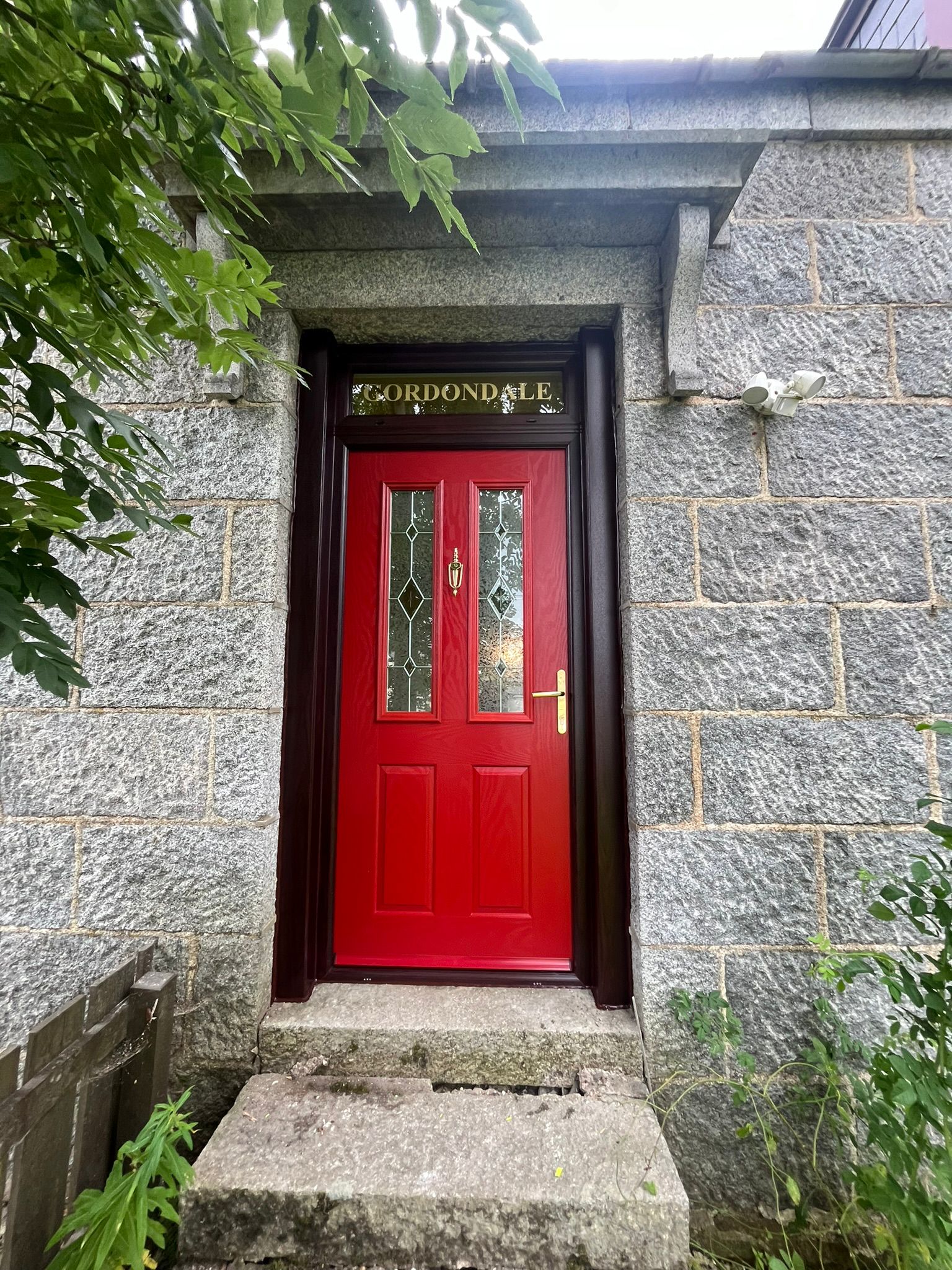 Red Gordondale composite door with leaded glass on granite cottage
