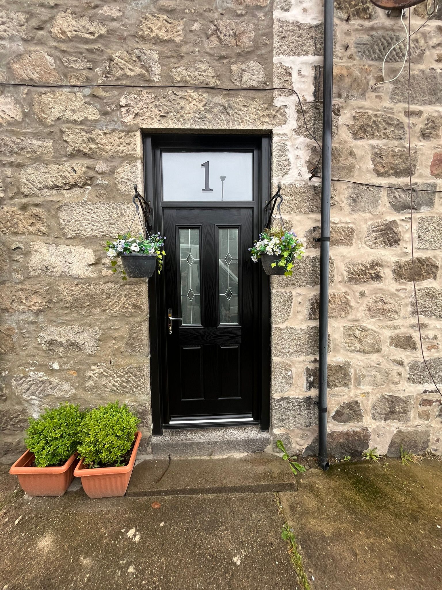 Black composite door with leaded glass and hanging baskets